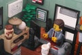 A Lego businessman minifigure sitting and working behind a computer in an office