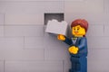 Lego businesswoman minifigure with brick ready to finishing gray wall Royalty Free Stock Photo