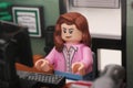 A Lego businesswoman minifigure sitting and working behind a computer in an office.