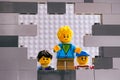 Lego children looking through a hole in gray wall