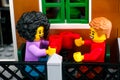 Lego couple minifigures with mugs sitting on the terrace