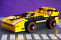 Lego custom made car on Lego road baseplate. Purple background