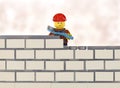 Lego minifigure worker by brick wall building Royalty Free Stock Photo