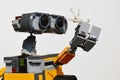 LEGO figure of Wall-E robot from Disney Pixar movie adoring white sea coral in his left arm, light grey background.