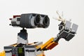 LEGO figure of Wall-E robot from Disney Pixar movie looking closely at white sea coral in his left arm, light grey background.