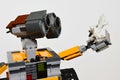 LEGO figure of Wall-E robot from Disney Pixar movie looking closely at white sea coral in his left arm, light grey background.