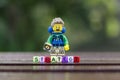 Lego hiker holding compass with word strategy using colorful alphabet beads.