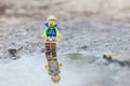 Lego hiker miniature with reflection on puddle.