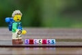 Lego hiker standing behind word success using colorful alphabet beads.