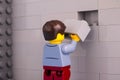 Lego man minifigure with brick ready to finishing gray wall Royalty Free Stock Photo