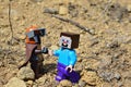 LEGO Mandalorian greets LEGO Minecraft Steve figure on arid desert like soil, summer daylight sunshine.