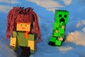 LEGO Minecraft action figure of Alex with dreadlock looking handmade winter cap chased by Creeper creature mob.