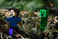 LEGO Minecraft action figure of Steve chased by green dangerous explosive mob called Creeper on pile of crushed fir-needles