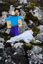 LEGO Minecraft action figure of Steve looking standing on rocks smiling at first real frozen snow.