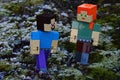LEGO Minecraft action figures of Alex and Steve on walk on real frozen moss, talking to each other.