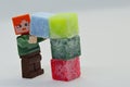 LEGO Minecraft Alex is lifting light blue cube made of stearine scented wax to place it on top of column of colorful wax cubes Royalty Free Stock Photo