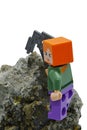 LEGO Minecraft figure of Alex with iron pickaxe mining Chalcopyrite mineral rock, white background.