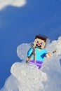 LEGO Minecraft figure of Steve trying to climb on real glacier mountain in winter landscape
