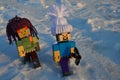 LEGO Minecraft figures of Steve and Alex with fashy handmade winter caps, walking through deep snowy field.