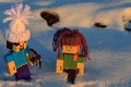 LEGO Minecraft figures of Steve and Alex with fashy handmade winter caps, walking in deep snow.