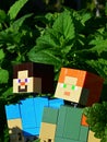 LEGO Minecraft figures of Steve and Alex standing in dense foliage of Lemon Balm Melissa Officinalis and Spearmint. Royalty Free Stock Photo