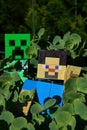 LEGO Minecraft large action figure of Steve chased by Creeper green explosive creature mob in dense foliage of succulent plant