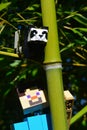 LEGO Minecraft large action figure of Steve looking at small LEGO Minecraft Panda bear sitting on side branch of real bamboo plant