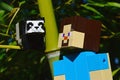 LEGO Minecraft large action figure of Steve looking at small LEGO Minecraft Panda bear sitting on side branch of real bamboo plant