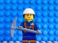 Lego miner with pickaxe against blue baseplate backgrounds