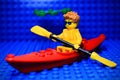 Lego mini-figure rowing boat across the river Royalty Free Stock Photo