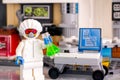 Lego minifigure in protective suit with green flask near working place in laboratory