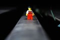 Lego movie hero standing on a black surface with dark, blurred background