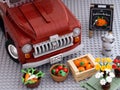 A Lego Pickup Truck with crates of vegetables, milk bucket, a wheelbarrow with flowers and sign Best from the Farm in front of it