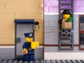 Lego police officer drinking coffee and eating a donut while a robber is climing a ladder to escape with a bag of money inside it