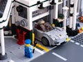 Lego Porsche 911 leaving a vehicle workshop. Lego mechanic minifigure standing near workshop outside