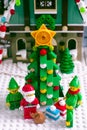 Lego Santa Claus and Elves standing near Christmas tree opposite Elf Club House