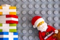 Lego Santa Claus and stack of presents on gray baseplate background.