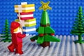 Lego Santa Claus with stack of presents near christmas tree