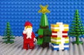 Lego Santa Claus and stack of presents near christmas tree