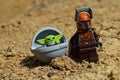 LEGO Star Wars Mandalorian figure in brown suit with cloak standing on arid desert surface with alien Yoda race Child