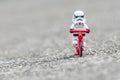 Lego storm trooper riding bicycle.