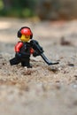 Lego Toy male figure character with a moustache, walking in the sand with a metal detector