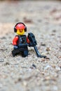 Lego Toy male figure character with a moustache, walking in the sand with a metal detector
