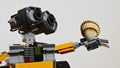 LEGO Wall-E robot holding bivalve seashell of Cockle family, in his left arm, light grey background.