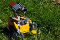 LEGO Wall-E toy robot from Disney Pixar animated science fiction movie just discovered a yellow blooming dandelion flower