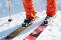 Legs athlete skier in an orange overall on a sport skiing on snow on a sunny day. The concept of winter sports