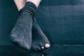 Legs bankrupt in black holey socks on a black background