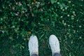 The legs of girl in a white  shoes are standing in the tall green grass Royalty Free Stock Photo