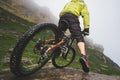 Legs of bicyclist and rear wheel close-up view of back mtb bike in mountains against background of rocks in foggy Royalty Free Stock Photo