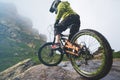 Legs of bicyclist and rear wheel close-up view of back mtb bike in mountains against background of rocks in foggy Royalty Free Stock Photo